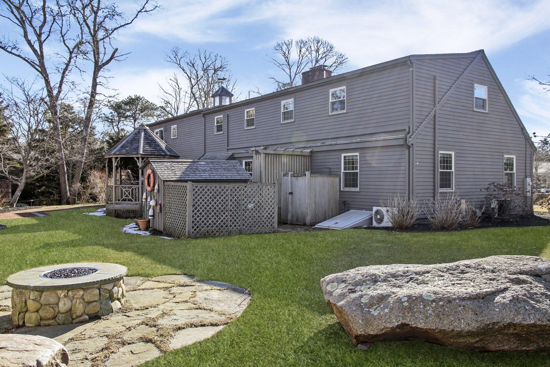 4 Shapquit Bars Road Falmouth, MA 02540 - Photo 32 of 45 a view of a backyard with table and chairs potted plants and large tree