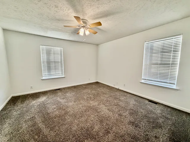 an empty room with windows and fan