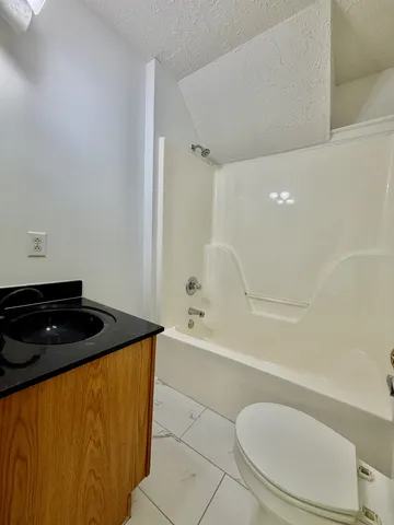 a bathroom with a granite countertop sink and a toilet