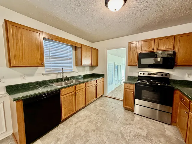 a kitchen with stainless steel appliances granite countertop a stove a sink and a microwave