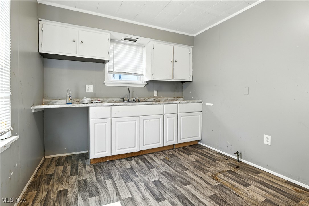 1774 Urbana Road Cleveland, OH 44112 - Photo 25 of 41 Kitchen featuring ornamental molding, wood finished floors, white cabinetry, and light countertops