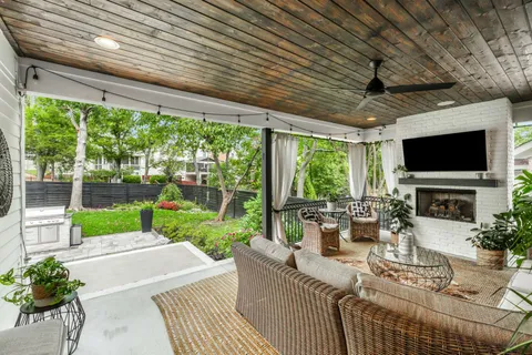 a view of a patio with couches chairs potted plants and a floor to ceiling window
