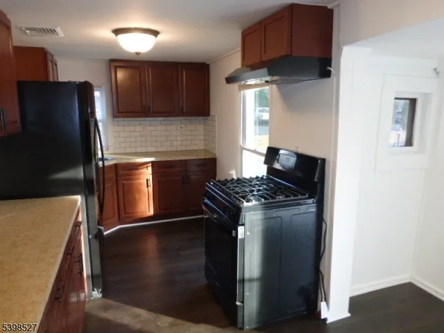 a kitchen with granite countertop a refrigerator stove and sink