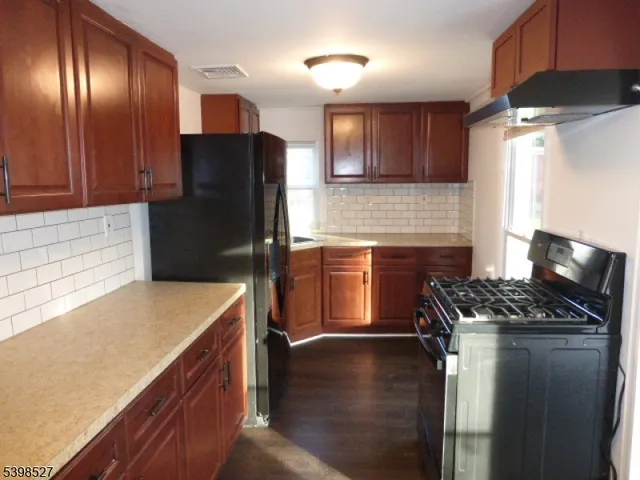 a kitchen with stainless steel appliances granite countertop a refrigerator a stove and a sink with wooden cabinets