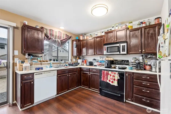 a kitchen with stainless steel appliances granite countertop a stove a sink dishwasher and a microwave oven with wooden cabinets