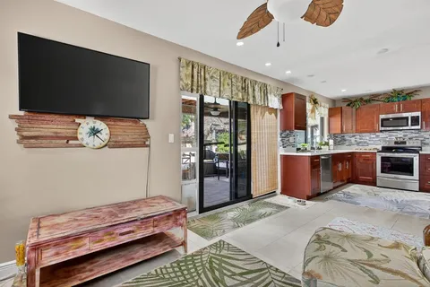 a room with kitchen island stainless steel appliances lots of wooden furniture and a flat screen tv