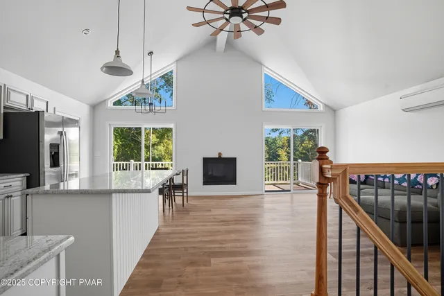 a view of a livingroom with furniture flat screen tv wooden floor and a ceiling fan