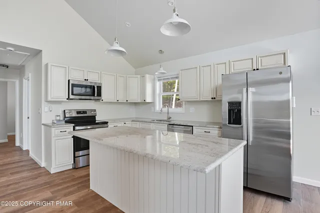 a kitchen with kitchen island granite countertop a stove sink and refrigerator