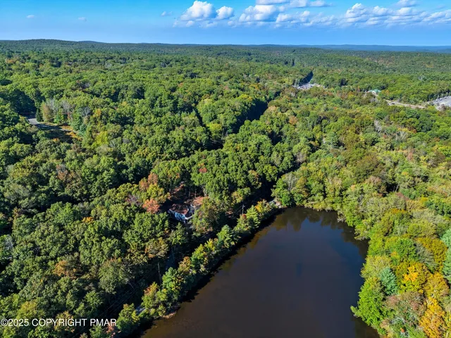 an aerial view of a residential houses with outdoor space and lake view