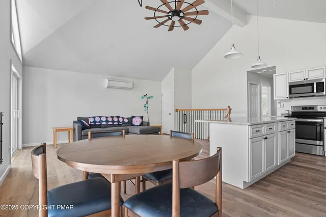 a kitchen with stainless steel appliances granite countertop a dining table chairs stove refrigerator and microwave