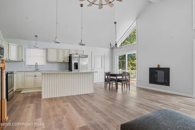 a kitchen with stainless steel appliances granite countertop a stove top oven a sink a dining table and chairs with wooden floor