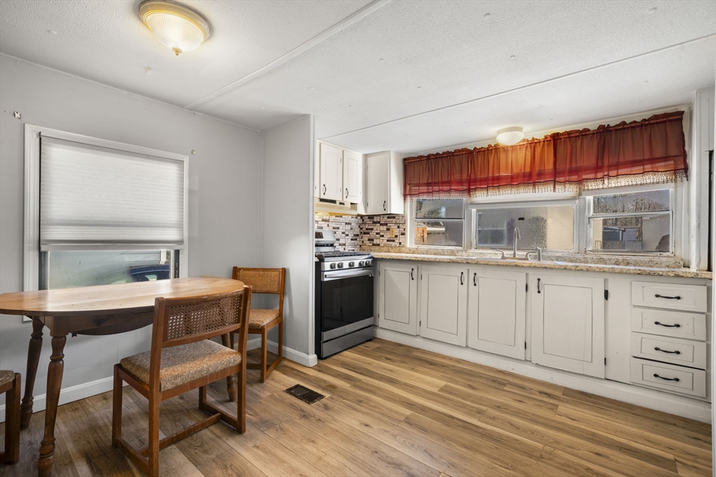 75 South Policy Street, Unit 48 Salem, NH 03079 - Photo 12 of 36 a kitchen that has a lot of cabinets in it with a dining table and chairs