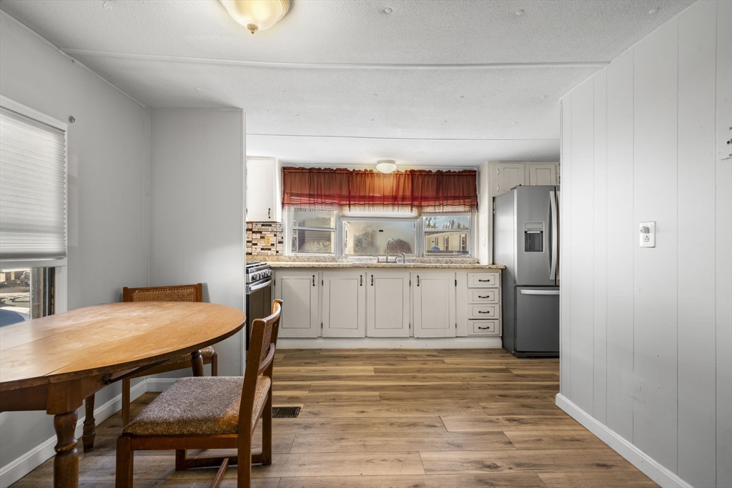 75 South Policy Street, Unit 48 Salem, NH 03079 - Photo 14 of 36 a kitchen with stainless steel appliances a dining table chairs and refrigerator