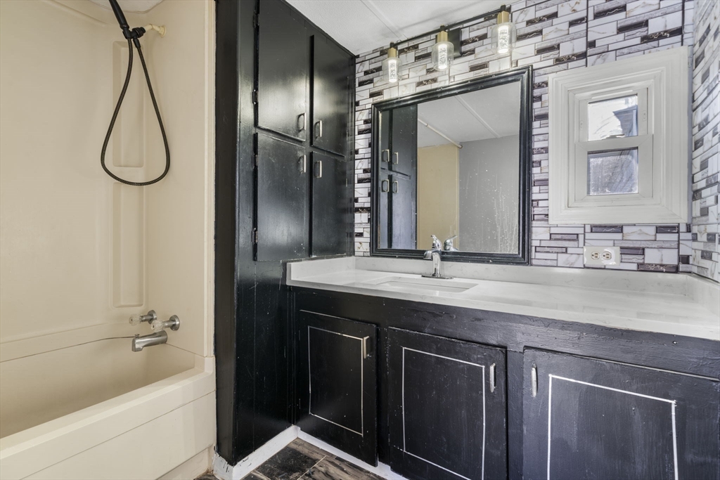 75 South Policy Street, Unit 48 Salem, NH 03079 - Photo 4 of 36 a bathroom with a granite countertop sink a mirror a vanity and bathtub