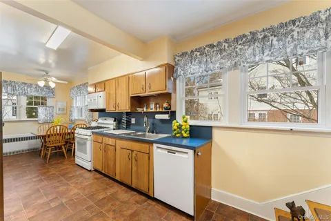 a kitchen with stainless steel appliances a sink a stove a refrigerator cabinets and a dining table