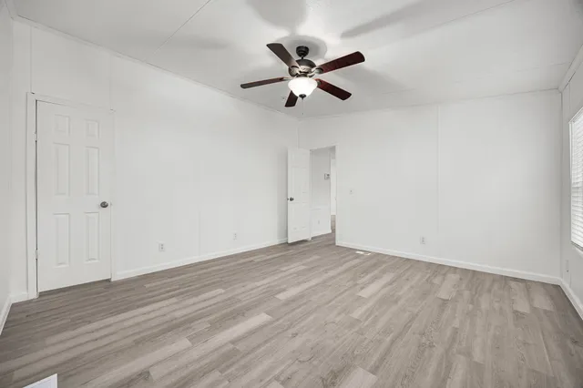 a view of a room with wooden floor and a ceiling fan
