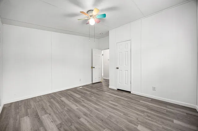 an empty room with wooden floor and ceiling fan