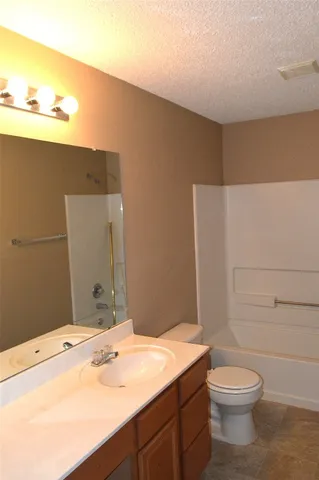 a bathroom with a granite countertop sink toilet and mirror