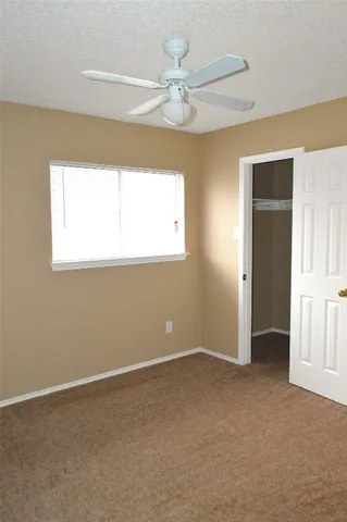 an empty room with a window and a chandelier fan