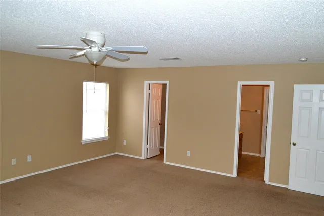 an empty room with windows and fan