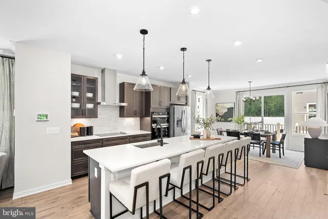 a view of a dining room and livingroom with furniture wooden floor a rug a fireplace and a chandelier
