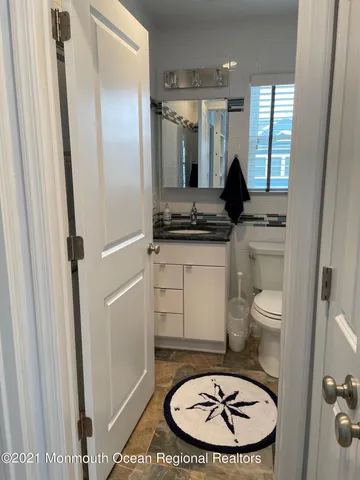 a bathroom with a granite countertop toilet a sink and a mirror