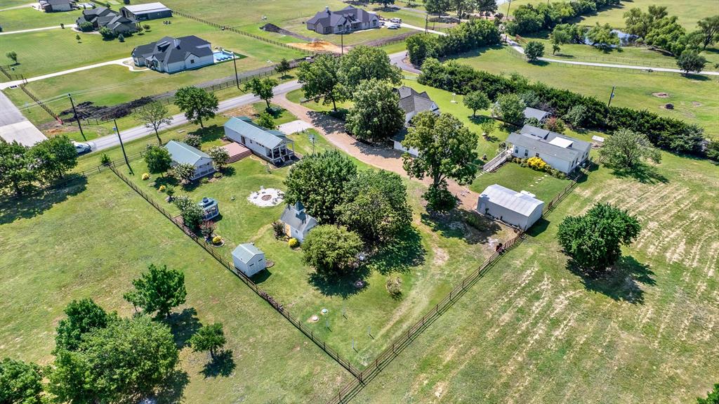 1425 Lone Star Road Celina, TX 75009 - Photo 38 of 40 From this angle, the property's park-like setting truly shines. Mature trees, open green space, and well-planned improvements—including the rental cottages, gazebo, pavilion, and gathering areas—create a welcoming environment with room to relax and entertain. The estate enjoys the peaceful feel of country living while being surrounded by attractive newer custom homes on large acreage tracts.