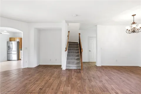 a view of an empty room with wooden floor and stairs