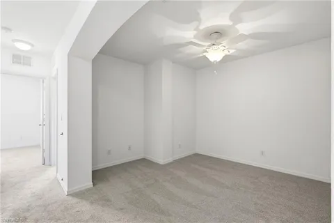 an empty room with a chandelier fan and windows