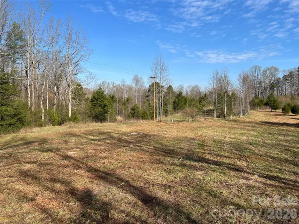 a view of dirt field with trees in the background