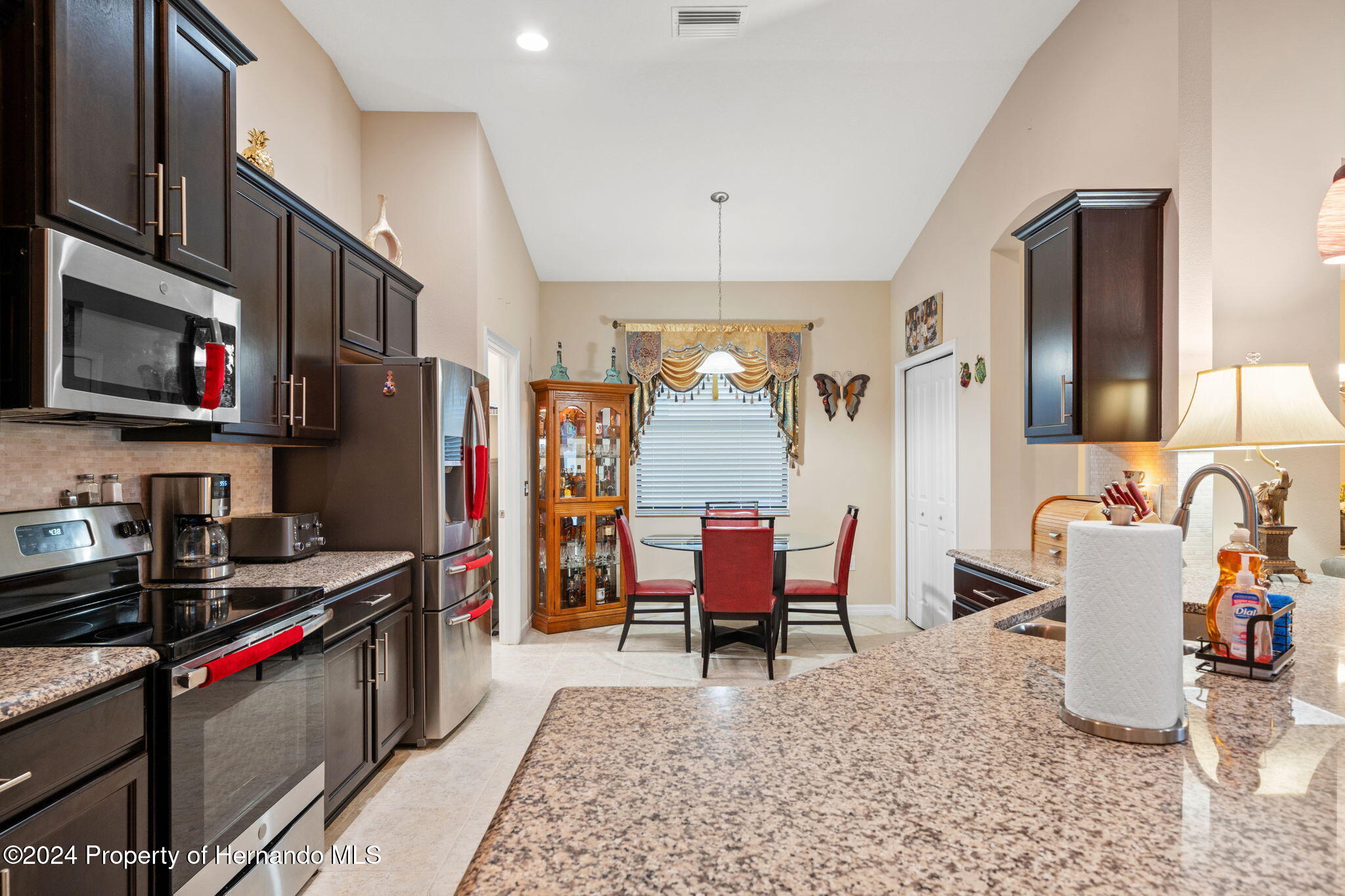 954 Old Windsor Way Spring Hill, FL 34609 - Photo 11 of 32 a kitchen with stainless steel appliances kitchen island granite countertop a refrigerator and a sink