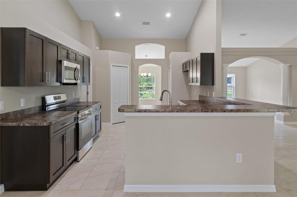 10342 Mirage Avenue Weeki Wachee, FL 34614 - Photo 15 of 45 a large kitchen with stainless steel appliances a large counter top a stove a microwave a sink and dishwasher