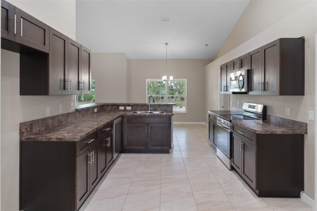 10342 Mirage Avenue Weeki Wachee, FL 34614 - Photo 20 of 45 a kitchen with stainless steel appliances granite countertop a stove a sink and a microwave