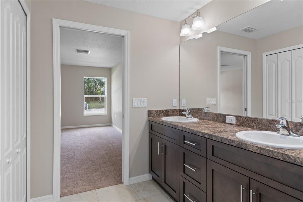 10342 Mirage Avenue Weeki Wachee, FL 34614 - Photo 33 of 45 a bathroom with a granite countertop double vanity sink a mirror and a shower