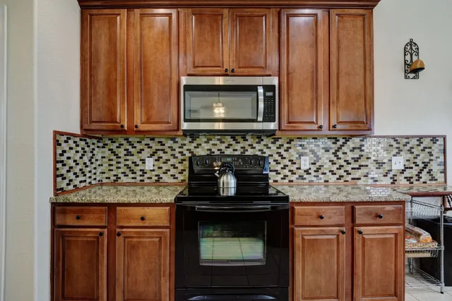 a kitchen with granite countertop a stove top oven microwave and cabinets