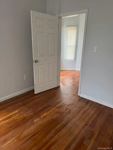 a view of an empty room with wooden floor and closet