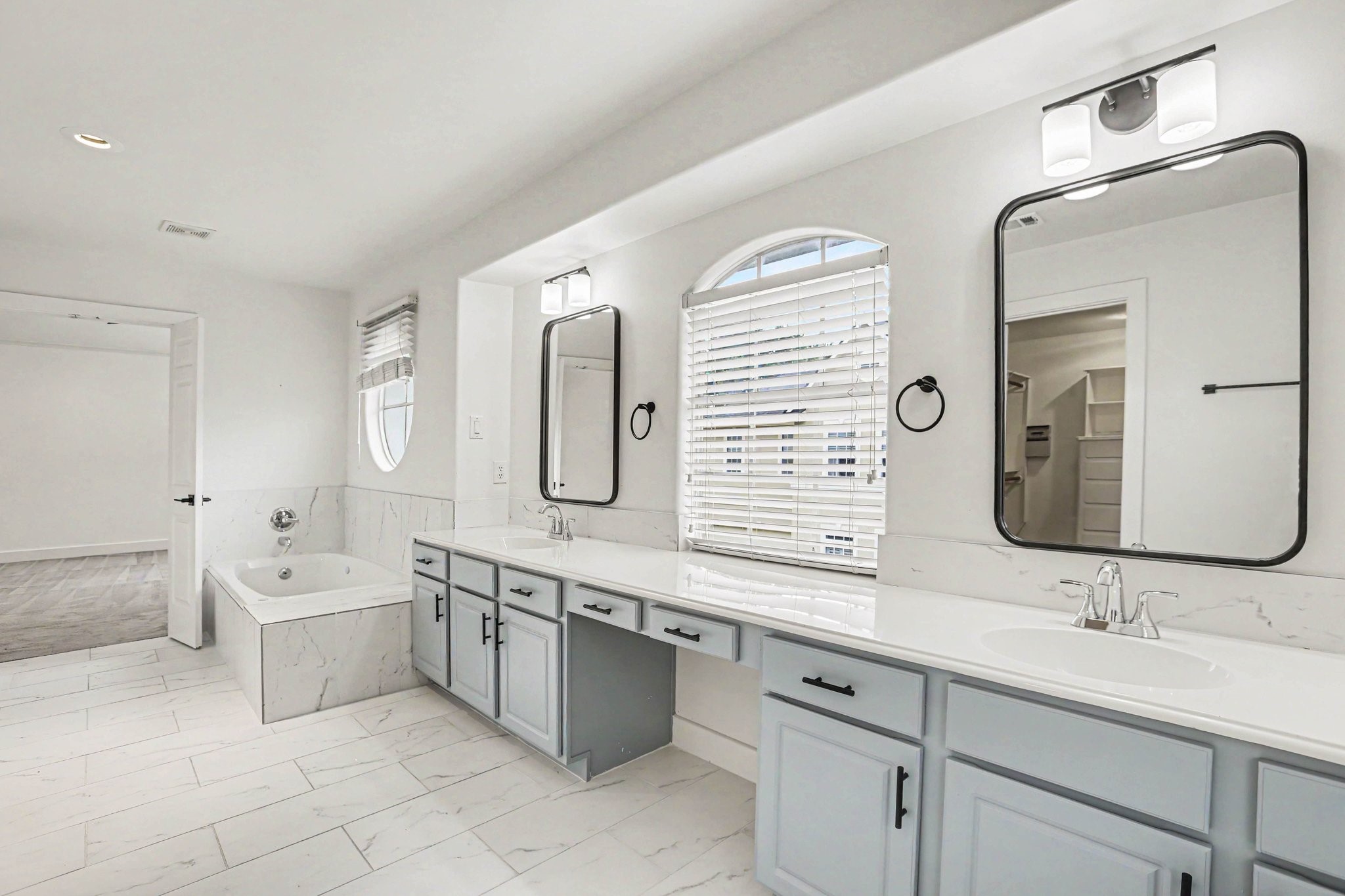 1470 Springrock Lane, Unit 6 Houston, TX 77055 - Photo 17 of 31 This is a spacious, bright bathroom featuring a walk-in shower, a bathtub, dual sinks with stylish mirrors, and a vanity area. It has modern fixtures and a sleek, minimalist design.