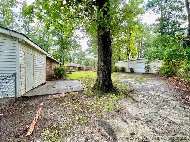 a view of a yard with large tree and wooden fence