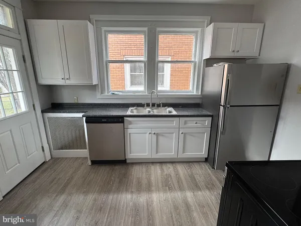 a kitchen with a refrigerator a sink and wooden floor
