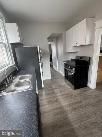 a kitchen with granite countertop a refrigerator stove and sink