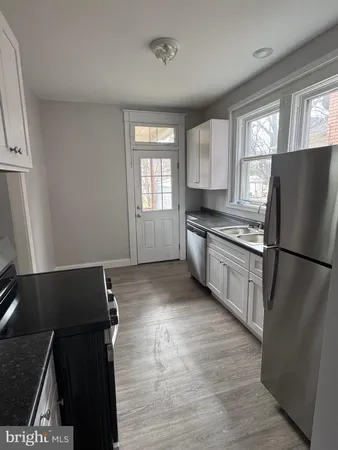 a kitchen with granite countertop a refrigerator and a stove top oven