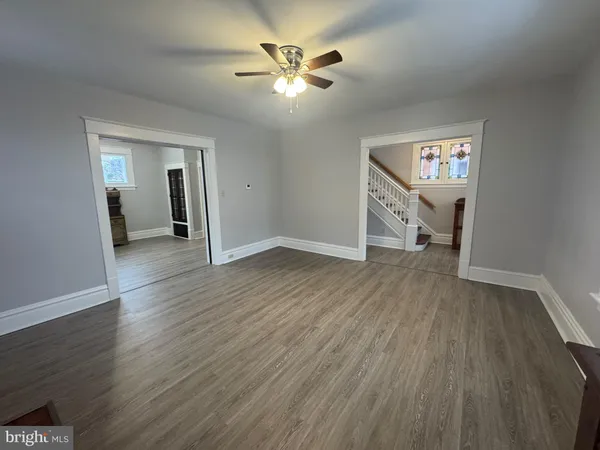 an empty room with wooden floor and a ceiling fan