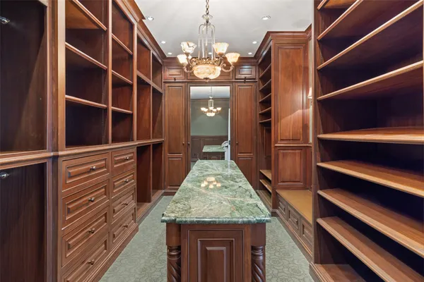 a bedroom with a bed a chandelier and a mirror on the dresser