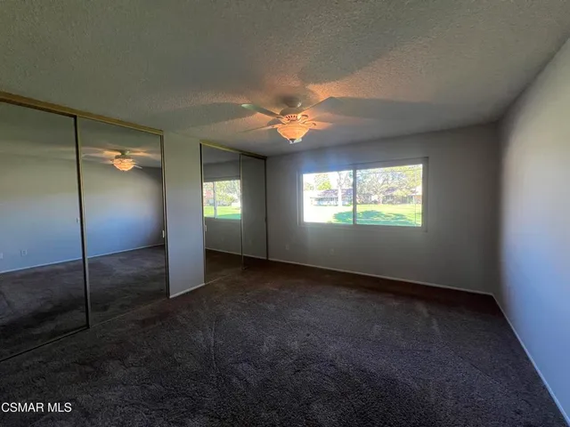 a view of an empty room with window and chandelier fan
