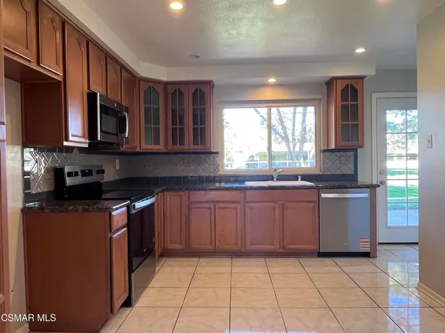 a kitchen with granite countertop a stove top oven microwave and cabinets