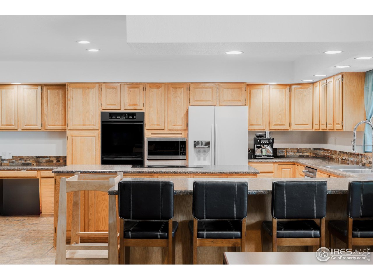 6789 Niwot Road Longmont, CO 80503 - Photo 14 of 28 a kitchen with stainless steel appliances granite countertop a stove top oven a sink a dining table and chairs