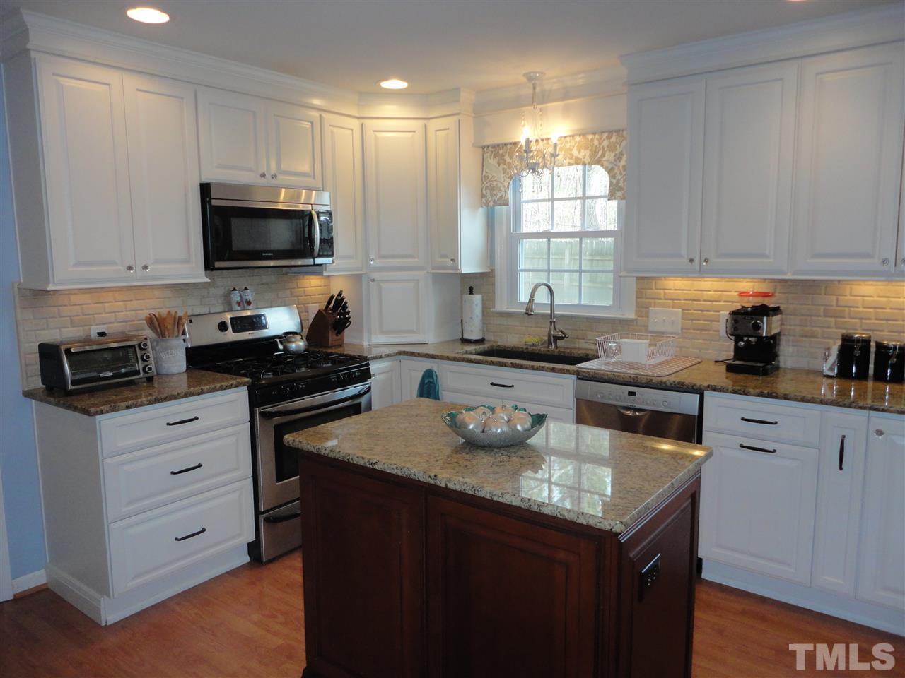 2369 Declaration Drive Raleigh, NC 27615 - Photo 6 of 20 a kitchen with granite countertop white cabinets sink and stainless steel appliances
