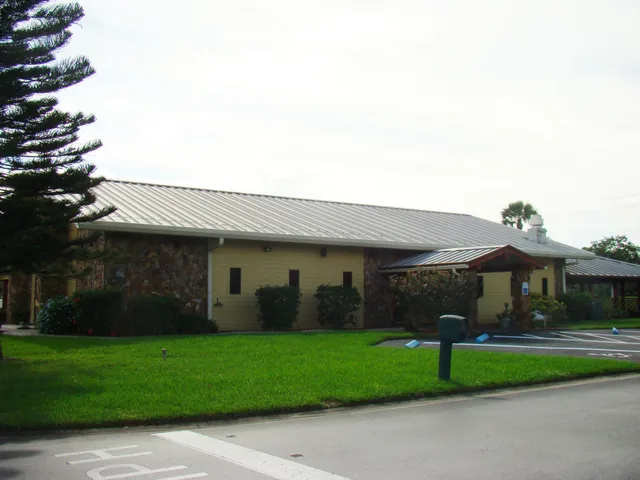 a view of a white house next to a yard with big trees