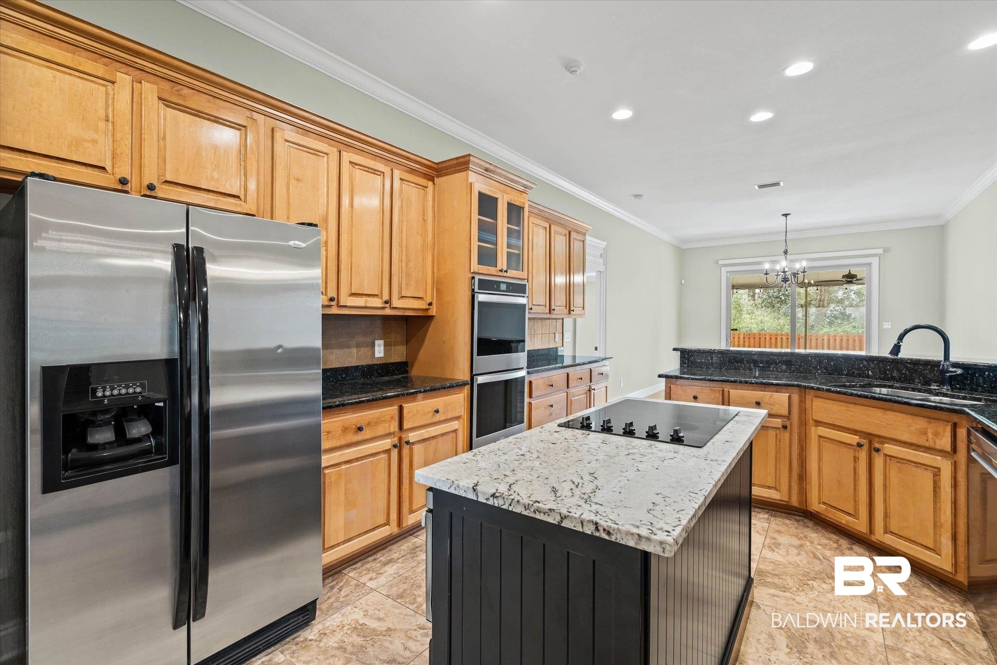 704 Edinburgh Avenue Foley, AL 36535 - Photo 13 of 32 Kitchen featuring stainless steel appliances, a kitchen island, glass fronted cabinets, a chandelier, and crown molding