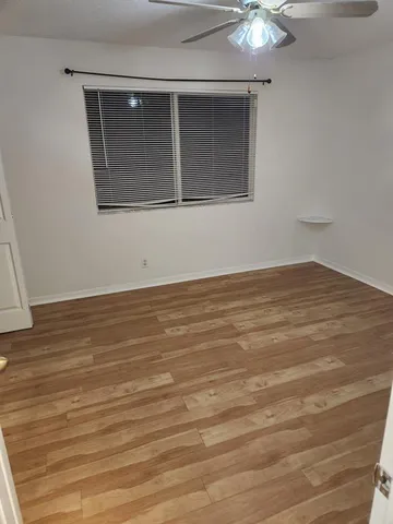a view of an empty room with wooden floor and a chandelier